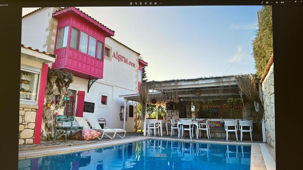 a swimming pool in front of a building with a table and chairs at Aişem By Hire in Alaçatı