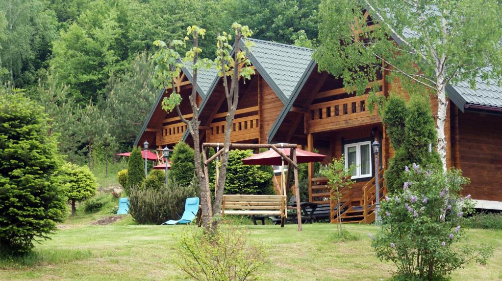 uma cabana de madeira com um banco e uma casa em Domki letniskowe Stary dąb em Solina