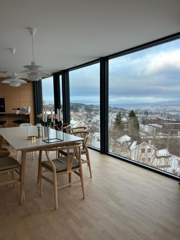 comedor con mesa, sillas y ventanas grandes en Villa Trondheim, en Trondheim