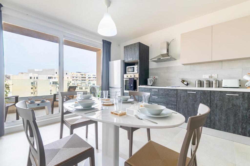 Il comprend une cuisine et une salle à manger avec une table et des chaises blanches. dans l'établissement Brand New Apartment 3Bdr 2 Bth H12, à San Pawl il-Baħar
