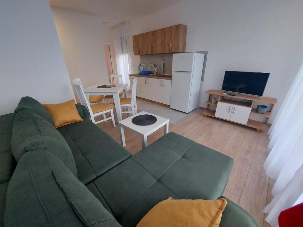 Una sala de estar con un sofá verde y una cocina. en Apartman Banjski Raj, en Vrnjačka Banja