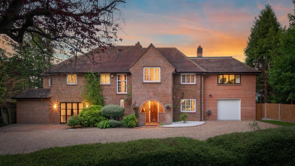 a brick house with a garage at sunset at Westleigh in Ashtead