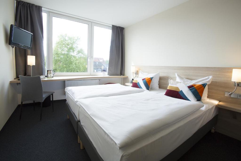 una habitación de hotel con una gran cama blanca y una ventana en Atlantic Hotel am Floetenkiel, en Bremerhaven