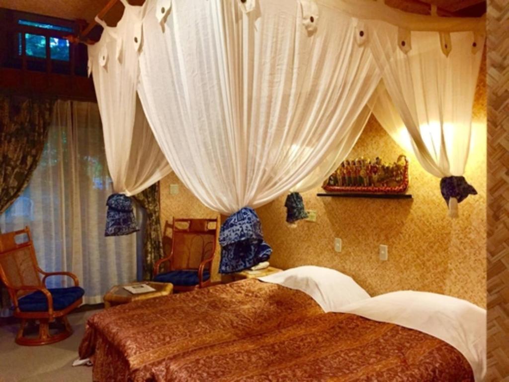 ein Schlafzimmer mit einem Bett mit Vorhängen darauf in der Unterkunft Estivant Club - Vacation STAY 95695v in Tsumagoi