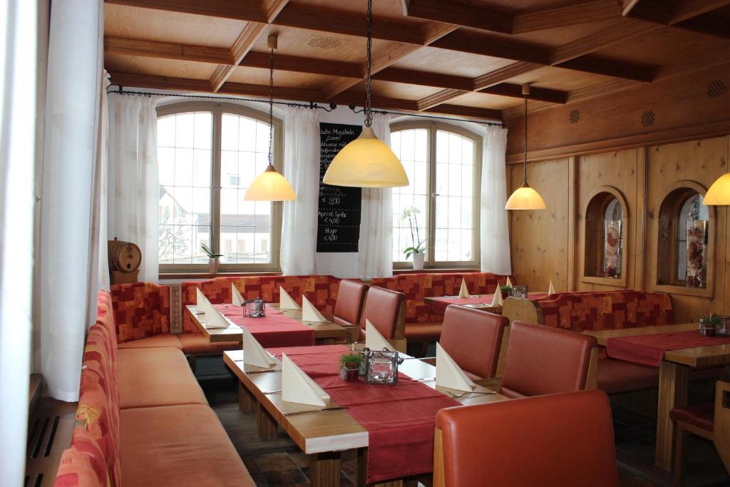 a restaurant with red tables and chairs and windows at Ristorante Pizzeria Pension Taormina in Roßhaupten