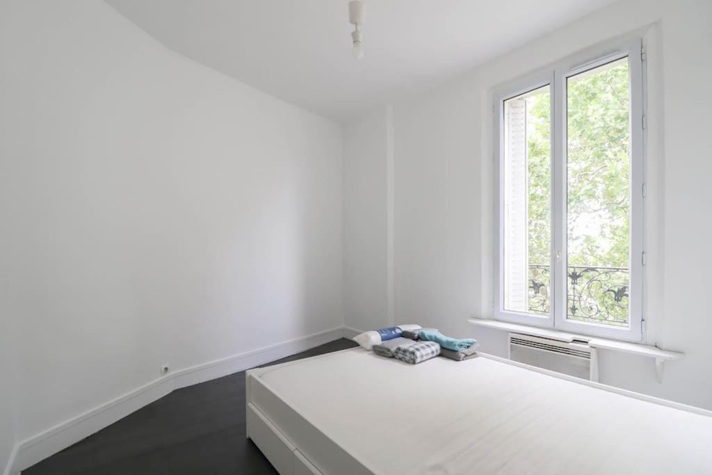 ein weißes Zimmer mit einem Bett und einem Fenster in der Unterkunft Montrouge 1 Bedroom Flat 30m2 - (2 pièces) in Montrouge