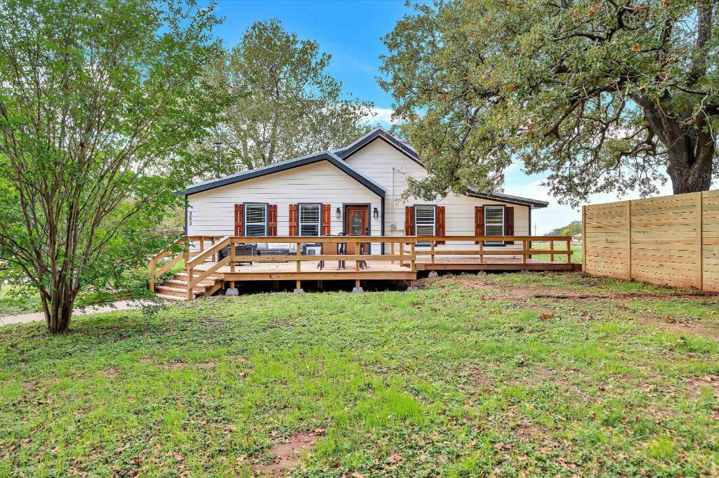 a house with a large deck and a fence at The Farmhouse 20 Min to Magnolia and Baylor in Waco