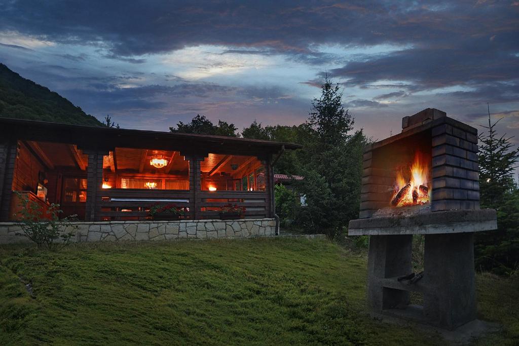 a log cabin with a fireplace in front of it at Cabana Poiana Verde in Slănic-Moldova