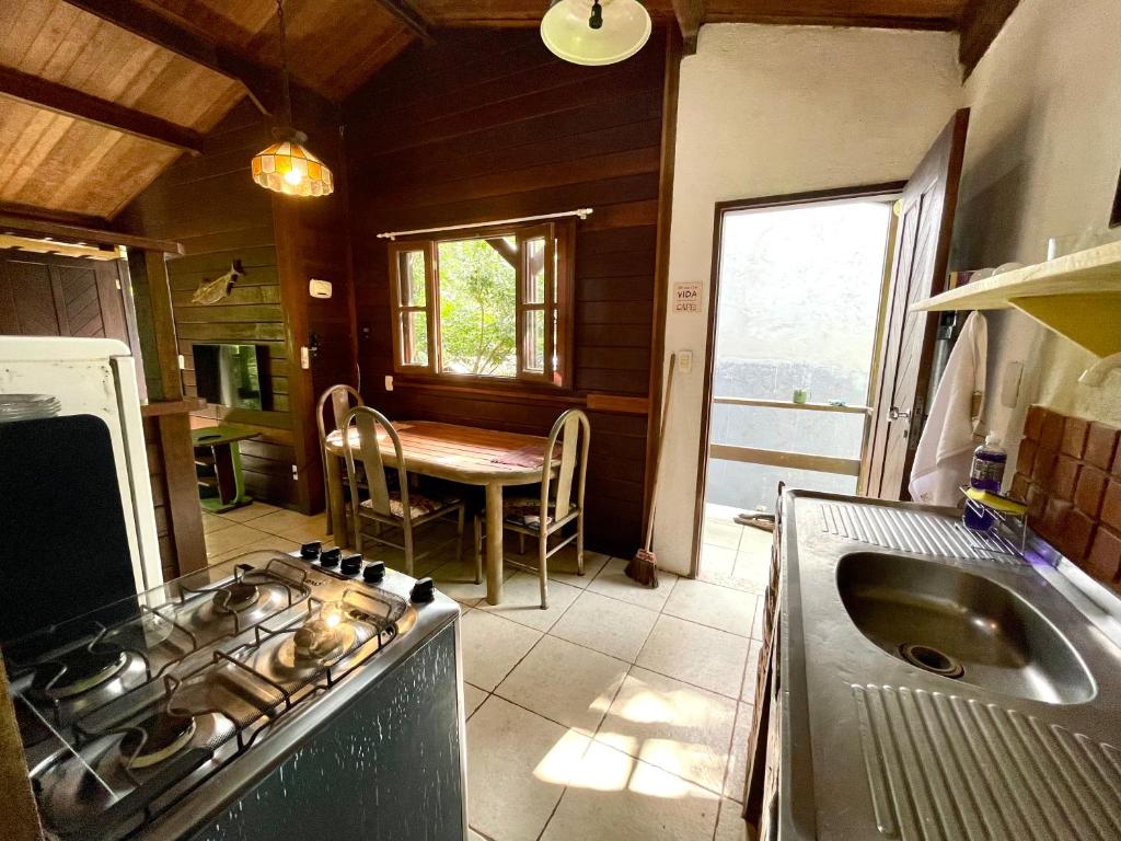 a kitchen with a stove and a sink and a table at Casa Selva - Vila do Abraão - Ilha grande in Abraão