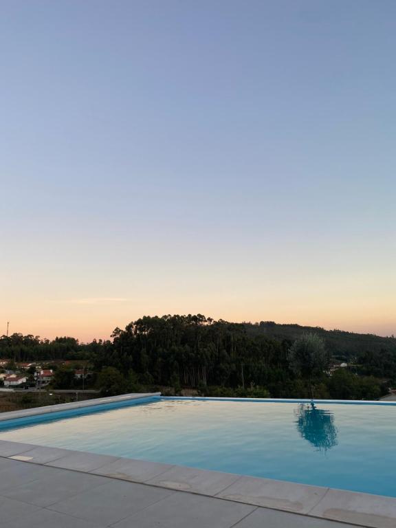 una gran piscina con puesta de sol en el fondo en CASA DAS QUINTÃES 