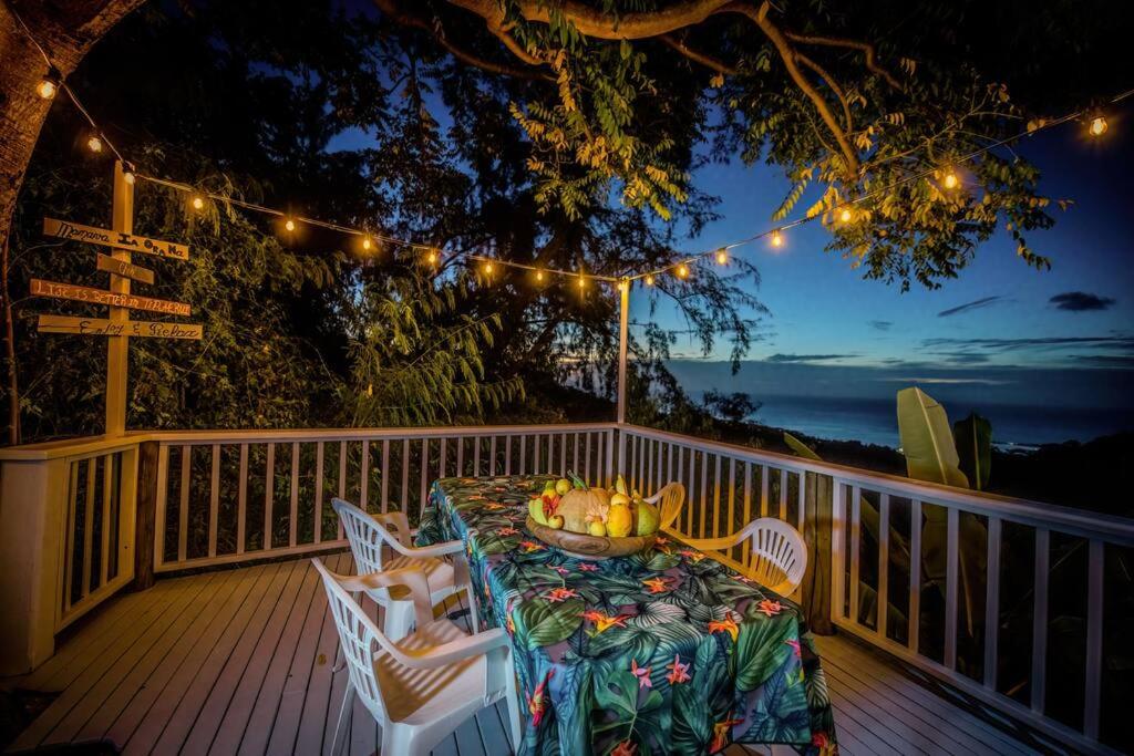 una mesa y sillas en una terraza con luces en Arevareva Pole House Papeete, en Papeete