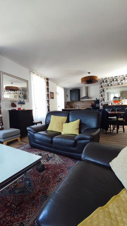 a living room with black leather couches and a table at le panoramique in Quimper