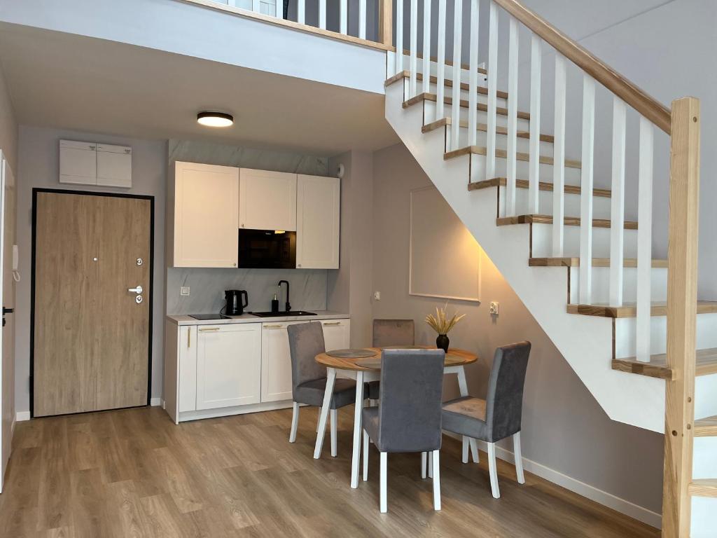 a kitchen and dining room with a table and a staircase at Apartament nr 24 Osada Cetniewo - Władysławowo-parking podziemny, duży balkon in Władysławowo