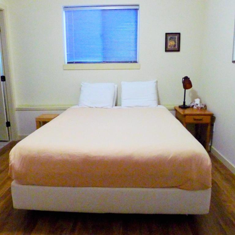 a bedroom with a white bed with a window and a table at AnnArthur Guest House in Nanaimo