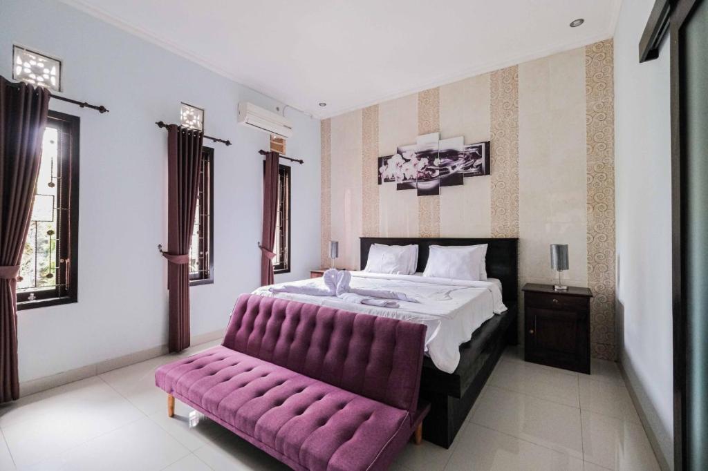 um quarto com uma cama grande e um banco roxo em The Fortune Guest House em Tejakula