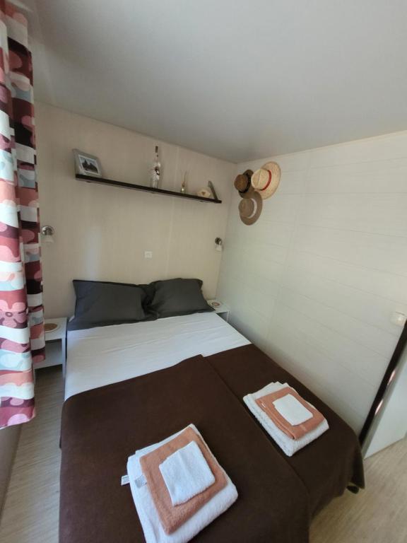 um quarto com uma cama com duas toalhas em Mobile-home hyeres var climatisé dans camping avec piscine jusqu'à 6 personnes em Hyères
