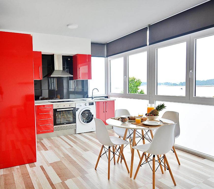 a kitchen with red cabinets and a table and chairs at Apartamentos de Playa en el centro de O Grove in O Grove