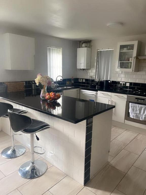 a large kitchen with a black counter and chairs at Harvard Road in Manchester