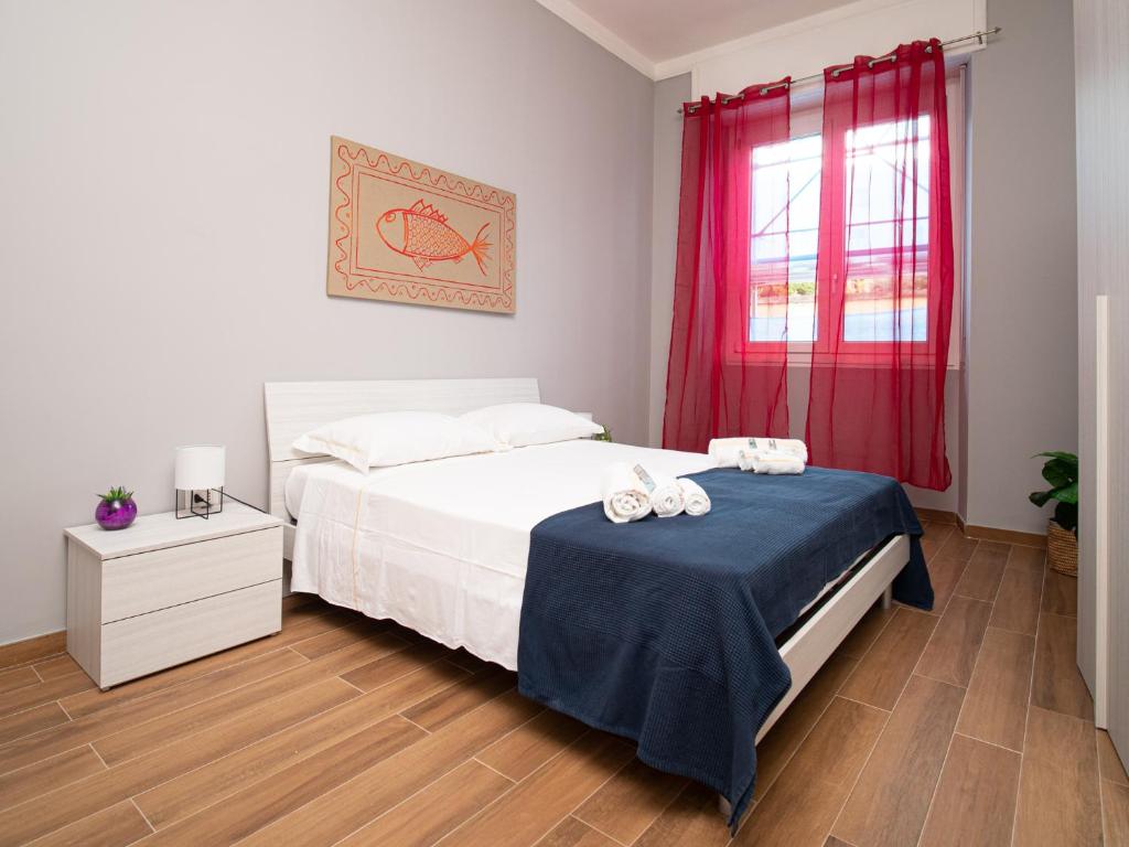 a bedroom with a bed and a window with red curtains at Maestrale Apartment in Cagliari