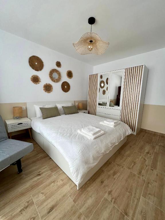 a bedroom with a large white bed and a chandelier at Lara Residence in Băile Herculane