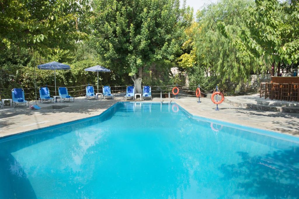 una gran piscina azul con sillas y sombrillas en Kotronas Bay Bungalows, en Kotronas