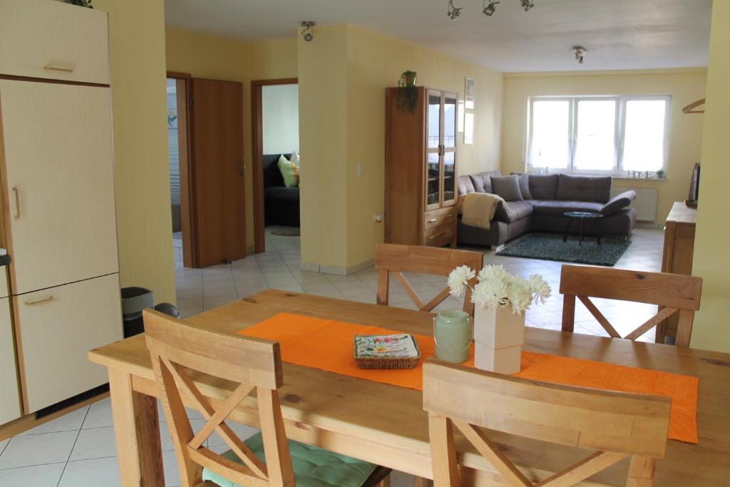 cocina y sala de estar con mesa de madera y sillas en Gemütliches Apartment, nahe Wetzlar en Wetzlar