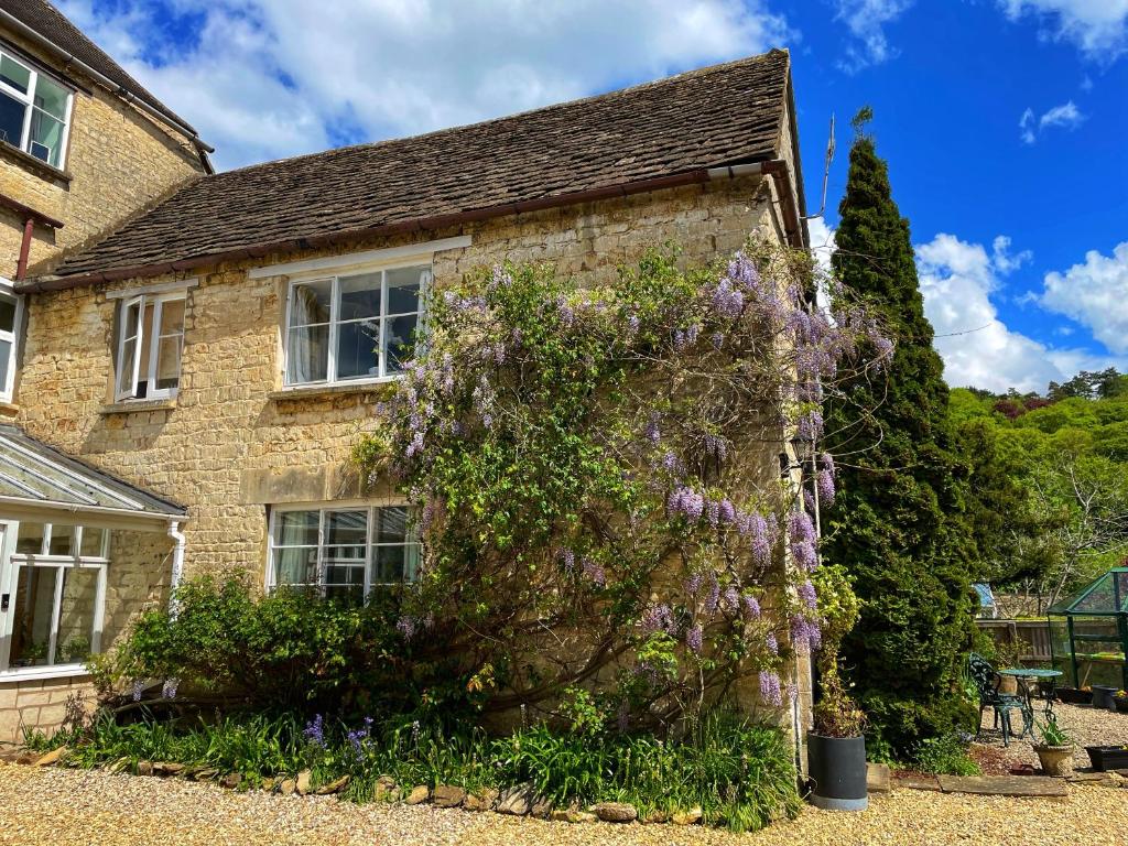 a house with purple flowers on the side of it at Cupcake Cottage: Quintessential Cotswold Cottage in Nailsworth