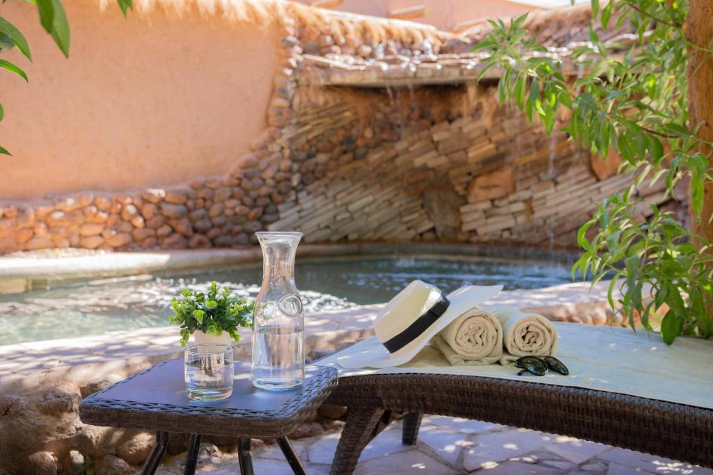 una mesa con un jarrón de cristal y servilletas sentadas junto a una piscina en Hotel Don Raul, en San Pedro de Atacama