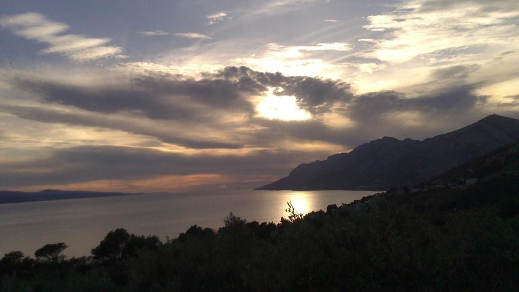 a sunset over a body of water with mountains at Holiday Home Oliveta in Brela