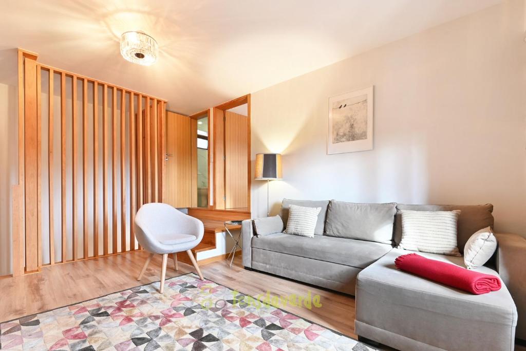 uma sala de estar com um sofá e uma cadeira em Casa do Alfaiate by TonsdeVerde em Vila Verde