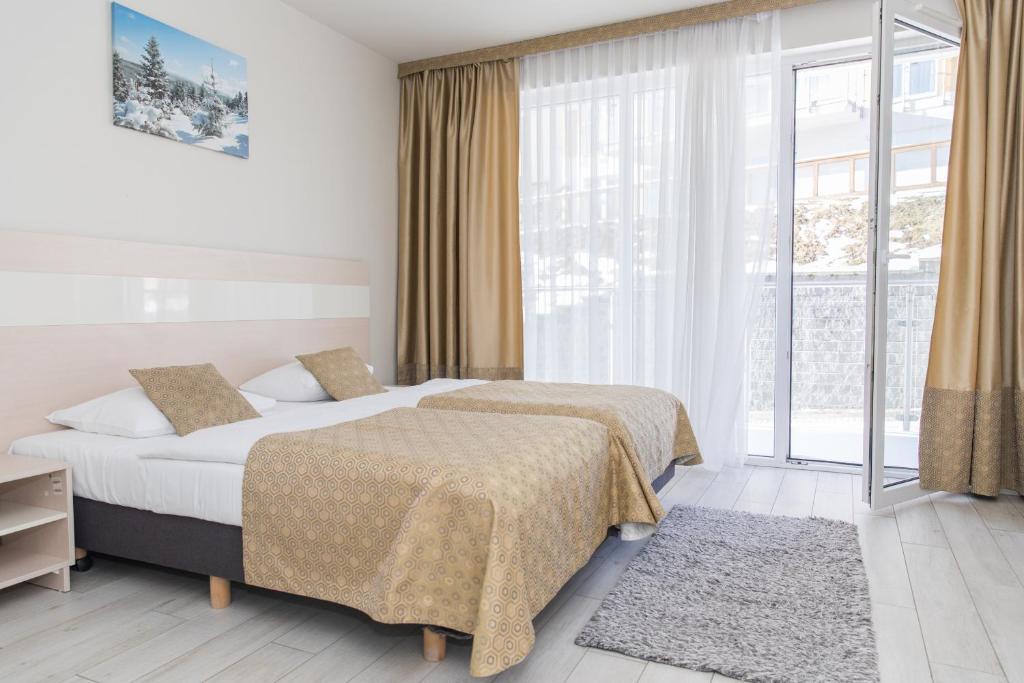 una camera d'albergo con due letti e una grande finestra di VacationClub - Solden Apartament 29 a Sienna