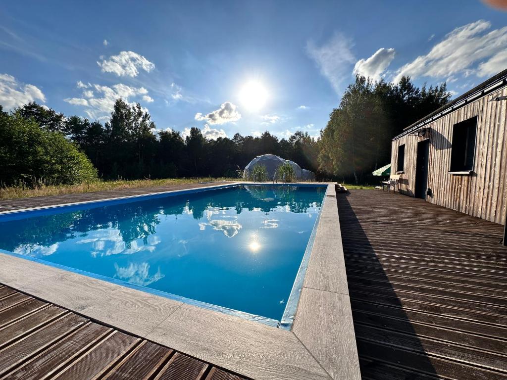 a swimming pool on a deck next to a building at Glamping Stodoła Dome in Ściegny