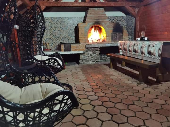 a living room with a fireplace with chairs and a bench at Casa Ispas in Râșca