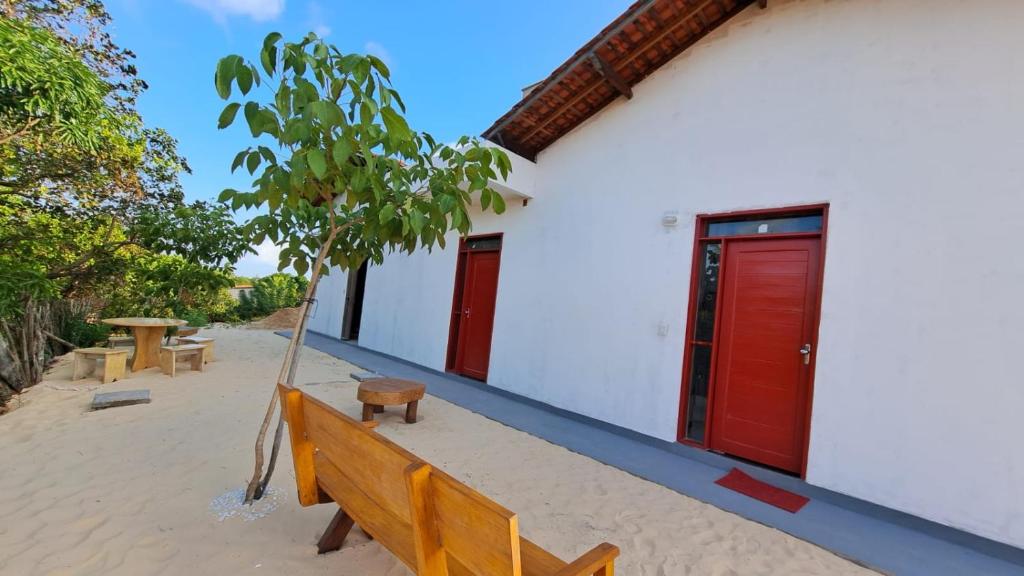una panchina di fronte a un edificio con porte rosse di Hostel Flor de Ipê a Barreirinhas