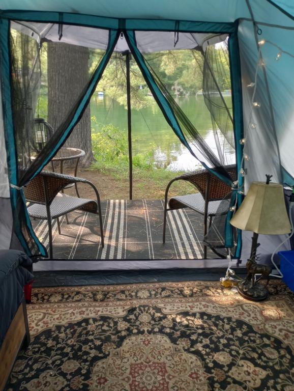 Washago的住宿－Glamping on the Green River，配有两把椅子、一张桌子和一盏灯的帐篷