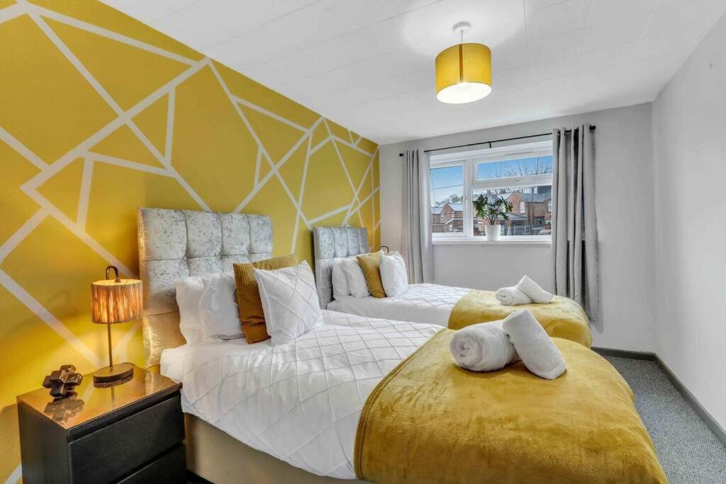 伯明罕的住宿－Stylish 3 Bed House Close to NEC，一间卧室设有两张床和黄色的墙壁