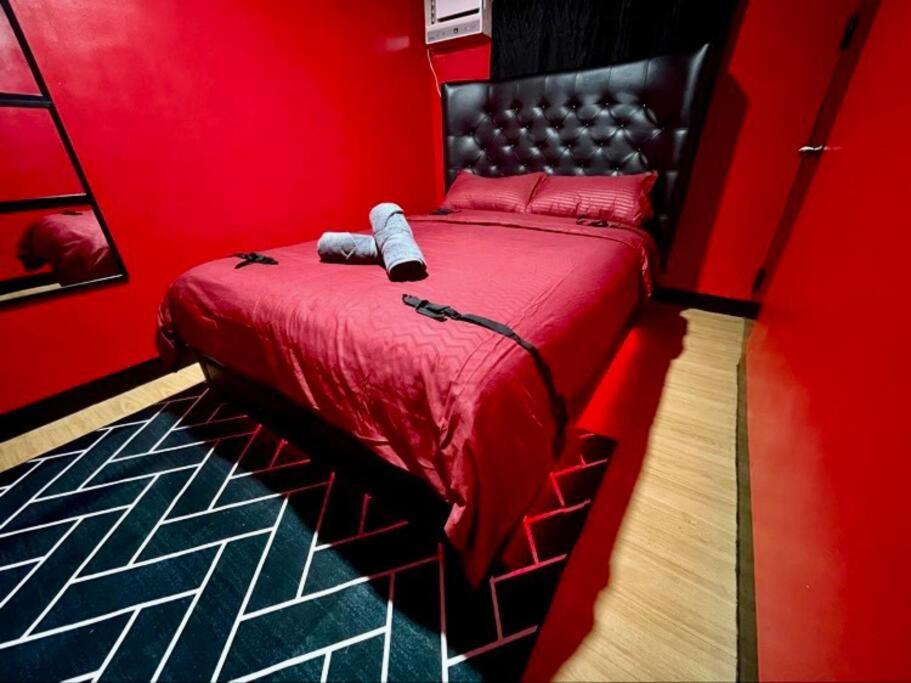 um quarto vermelho com uma cama com uma parede vermelha em The RedRoom 1Bedroom Staycation em Anabu Primero