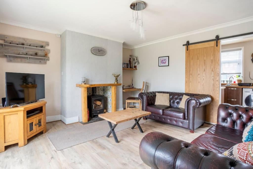 a living room with a leather couch and a fireplace at The Colliery House in Ebchester