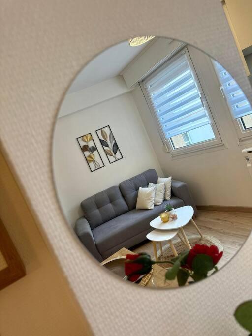 a living room with a blue couch and a round mirror at Appartement neuf entièrement équipé proche centre in Amiens