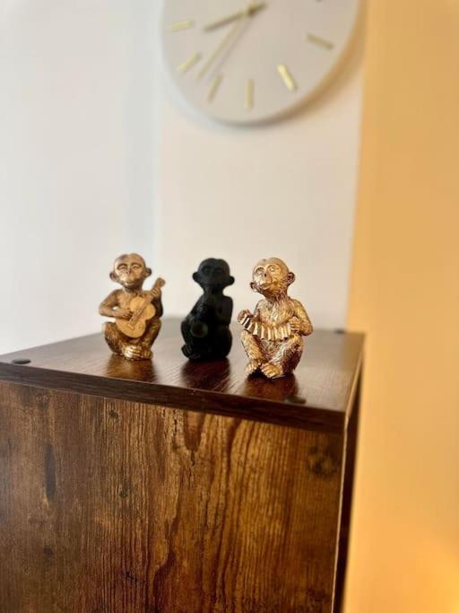 three small figurines sitting on a wooden shelf with a clock at Appartement neuf entièrement équipé proche centre in Amiens