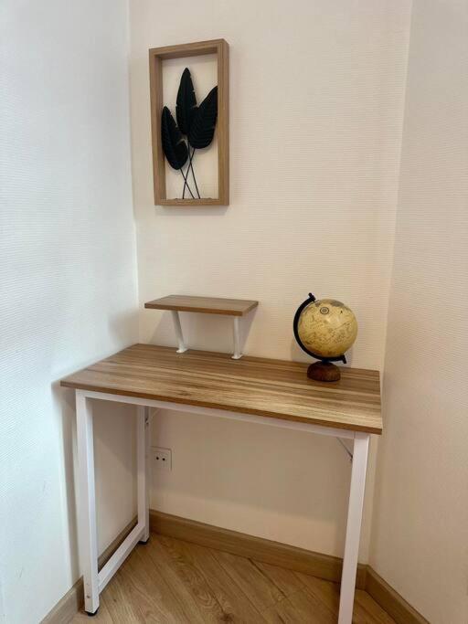 a wooden table with a picture of butterflies on the wall at Appartement neuf entièrement équipé proche centre in Amiens