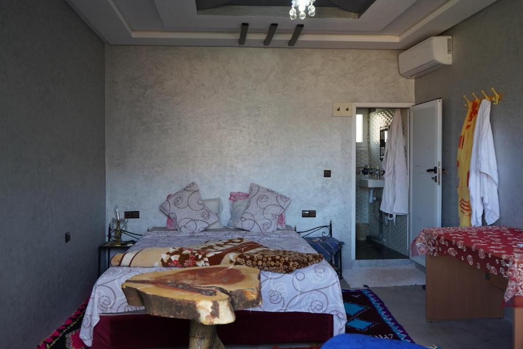 Un dormitorio con una cama y una mesa. en Chez Imnir en Ijjoukak