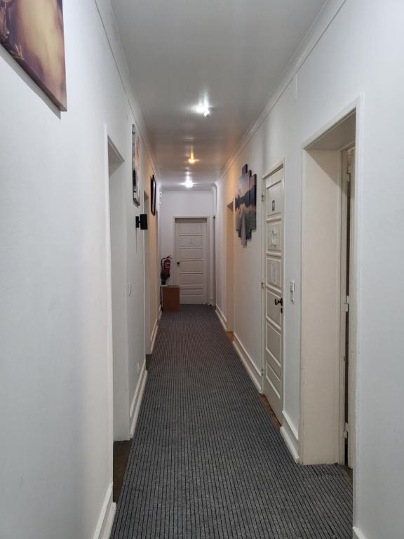 um longo corredor com paredes brancas e uma porta branca em Rose view guest house em Lisboa