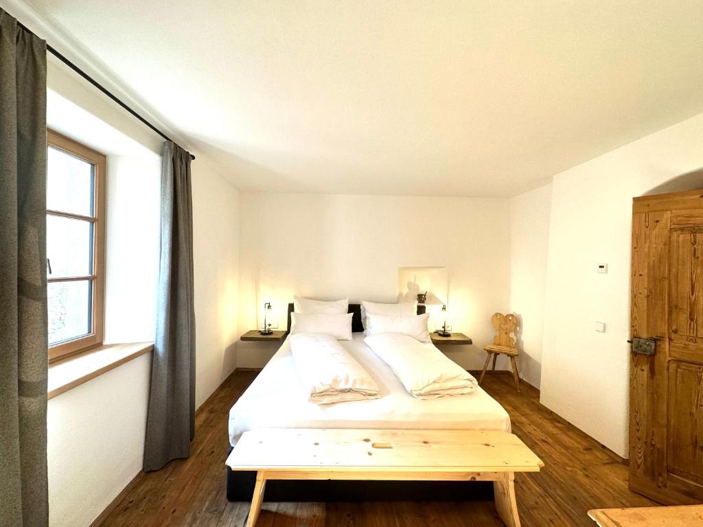 a white bedroom with a bed and a window at Landhaus Breitenberg in Lana