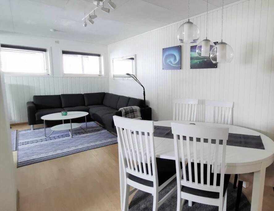 sala de estar con sofá, mesa y sillas en Spacious apartment on Kvaløya en Kvaloysletta