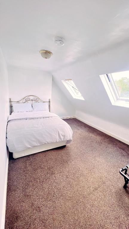 a white bedroom with a bed and two windows at Cozy and peaceful in London