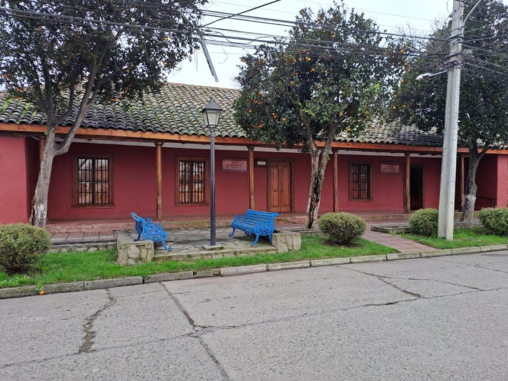 dos bancos azules frente a un edificio rojo en Hotel Artesanos, en Villa Alegre