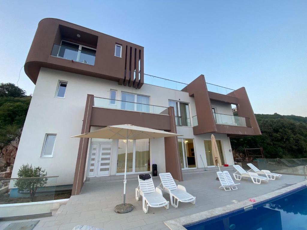 a house with chairs and an umbrella next to a swimming pool at Villa La Reina in Bar