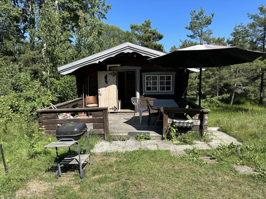 a cabin with an umbrella and a table and a grill at House in Akersberga Stockholm Beach and Sea in Åkersberga