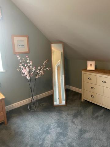 a room with a vase of flowers and a dresser at Meadow Bank, fabulous apartment in Baddiley